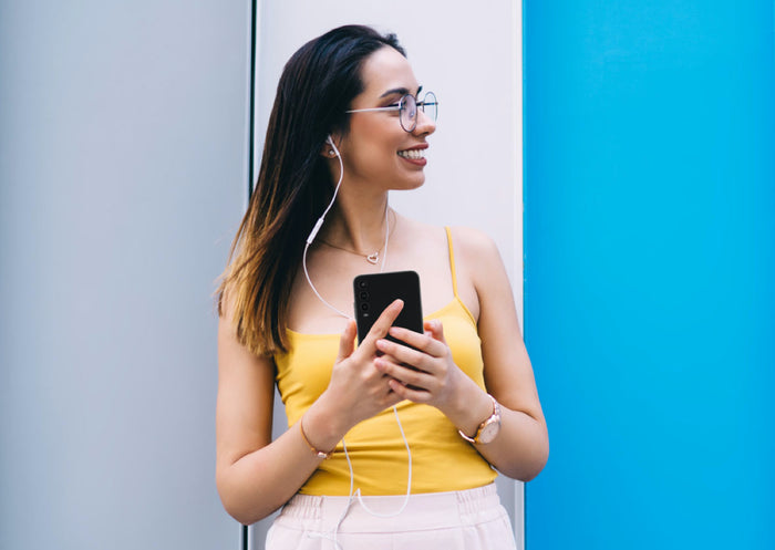 Woman wearing headphones and holding mobile phones